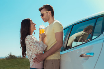 Orange juice. Caring dark-haired woman respecting eco food giving some fresh orange juice her man