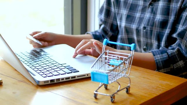 online banking , shopping concept. female hand holding a credit card and shopping online. shopping online with credit card at home lifestyle, shopping cart in foreground