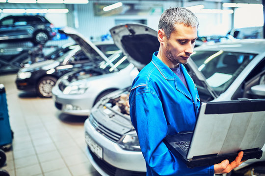 mechanic man with automotive diagnostic scanner and clipboard checking car system at workshop