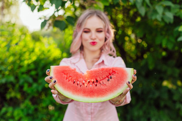 Beautiful young woman with pink hair holding watermelon