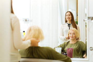 Fototapeta premium Your hairstyle. Nice cheerful woman speaking to the client while discussing her hairstyle