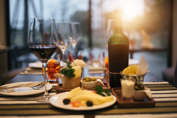 Red wine glass with Cheese plates served with tomato and 
olive