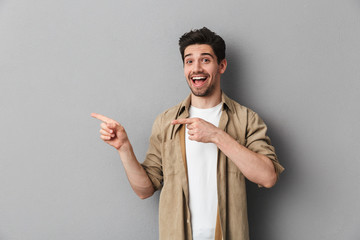 Portrait of a happy young casual man pointing away