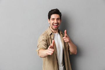 Portrait of a happy young casual man pointing at camera