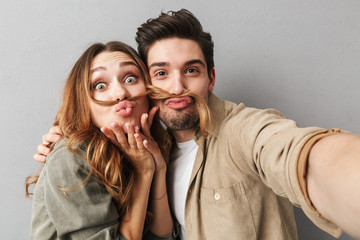 Portrait of a funny young couple hugging taking a selfie - obrazy, fototapety, plakaty