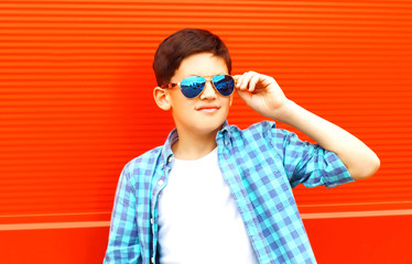 closeup portrait teenager boy in a sunglasses on a colorful orange background