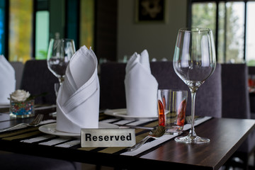 Reserved sign on a table in restaurant. Empty glasses set in restaurant