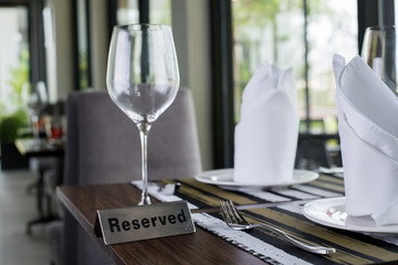 Reserved sign on a table in restaurant. Empty glasses set in restaurant