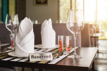 Reserved sign on a table in restaurant. Empty glasses set in restaurant