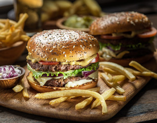 Hamburgers and French fries on the wooden tray.