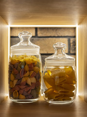 Colored pasta on a shelf in a glass jar in a modern interior
