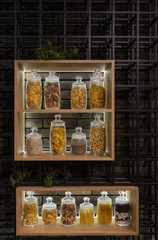 A lot of variable jars on a shelf in a modern interior with pasta, spaghetti, peas and rise
