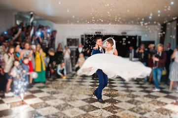 Gorgeous wedding couple performing their first dance with confetti, colorful lights and fireworks.