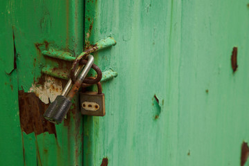 Green door is closed on two padlocks. Double protection