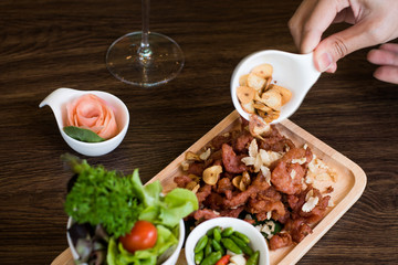 Fried Pork with Garlic. Deep Fried Crispy Pork Belly Cooked with Garlic and spicy dipping sauce on wooden table background