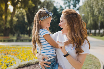 Fototapeta premium From kindergarten. Appealing mother feeling cheerful taking her cute little girl from kindergarten
