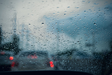 Car window with rain drops on glass or the windshield,Blurred traffic on rainy day in the city