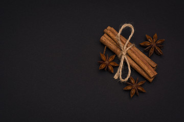 cinnamon sticks and cardamom on a black background top view with copy space for text