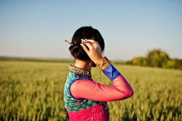 Tender indian girl in saree, with violet lips make up posed at field in sunset. Fashionable india...