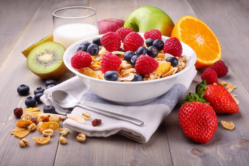 Breakfast with muesli cereal, milk and fruit: kiwi, apple, orange, soft fruits