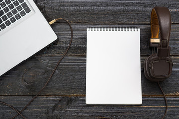 a laptop, headphones and blank Notepad on the desktop
