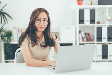 Fototapeta premium Happy young businesswoman with glasses working on computer laptop in home office