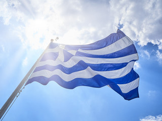 Official flag of Greece waving on a cloudy sky.