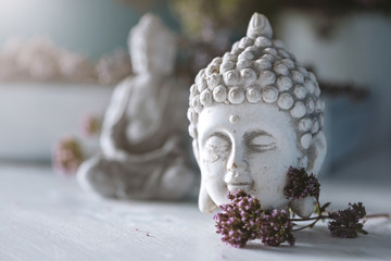 Gros plan sur la tête de bouddha avec une petite statue de bouddha en arrière-plan dans un jardin zen