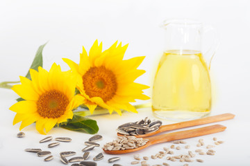 Freshly squeezed sunflower oil in a glass jug with sunflower seed on white background