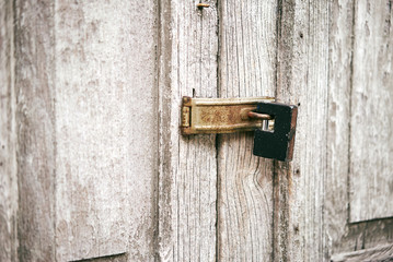 The old white door with stained locked with the black key on hinge