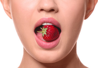 Sexy young woman with strawberry in mouth on white background, closeup