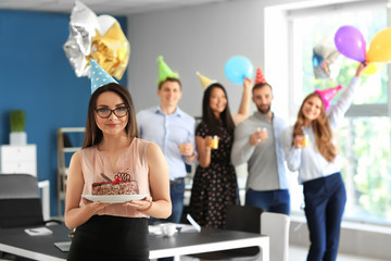Young woman with birthday cake at party in office