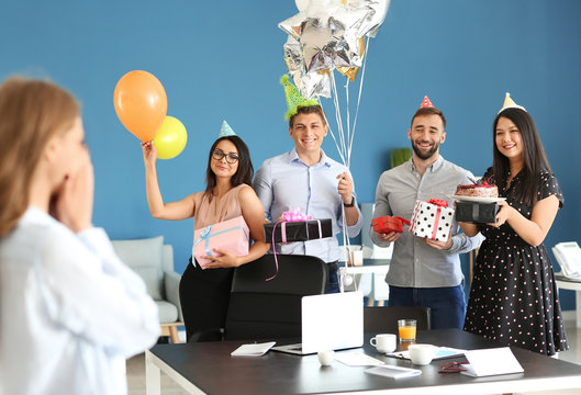 Happy Colleagues At Surprise Party For Young Woman On Her Birthday In Office