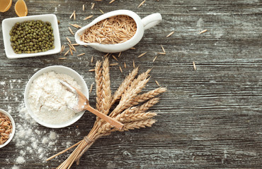 Composition with wheat flour, grains and spikelets on wooden background