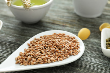 Plate with wheat grains on wooden table