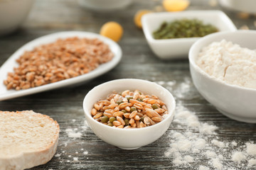 Bowl with wheat grains and beans on wooden table