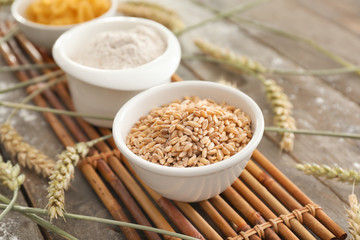 Bowl with wheat grains on wooden table