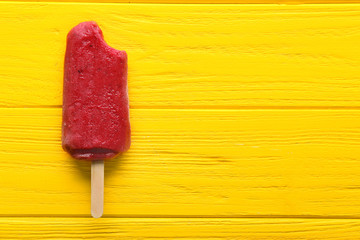 Delicious strawberry popsicle on color wooden background