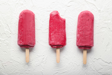 Delicious strawberry popsicles on light background