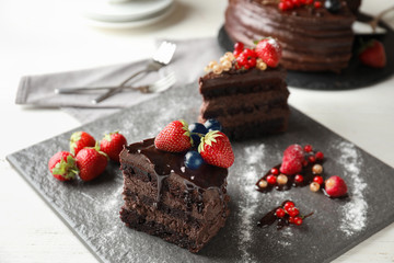 Piece of delicious chocolate cake with berries on slate plate