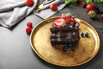 Piece of delicious chocolate cake with berries on metal tray
