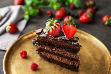 Piece of delicious chocolate cake with berries on metal tray, closeup
