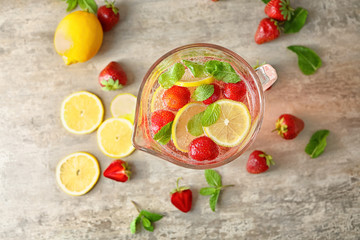 Natural lemonade with strawberries in glass jug on table