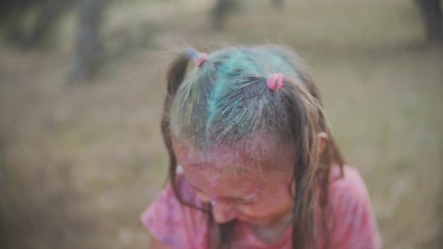 little girl painted with colors Holi sprinkle water in the face