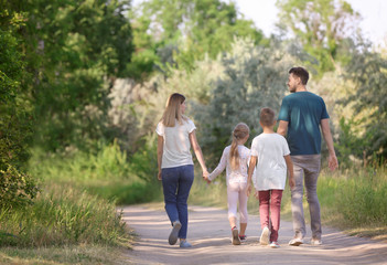Naklejka na ściany i meble Family walking in park on summer day