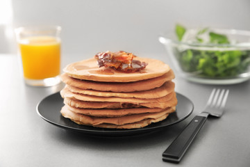 Plate with tasty pancakes and bacon on light table