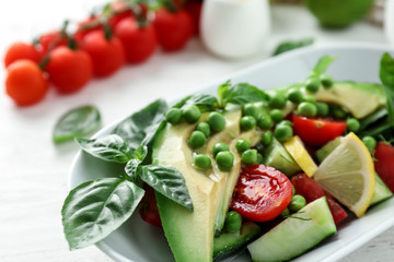 Tasty salad with avocado, tomatoes and green peas on plate, closeup