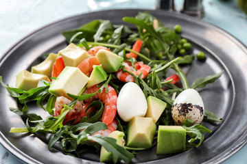 Tasty salad with avocado, quail eggs and shrimps on plate, closeup