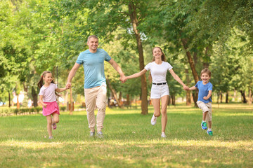 Fototapeta premium Happy family walking together in green park
