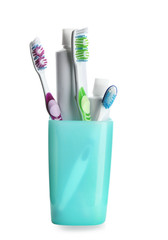 Cup with toothbrushes and paste on white background